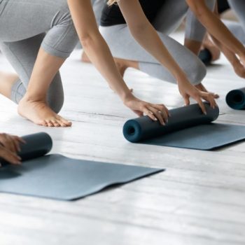 Diverse,Young,People,Wearing,Sportswear,Folding,Yoga,Mat,On,Floor
